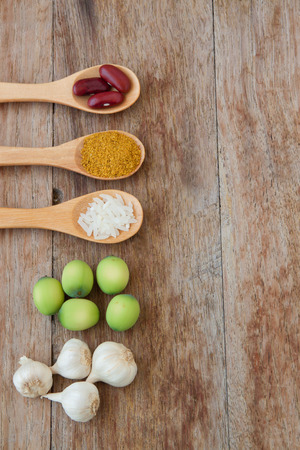 Herbs and spices in wooden spoons on wooden backgroundの写真素材