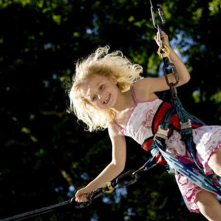 young girl bunji jumping securely on trampolineの写真素材