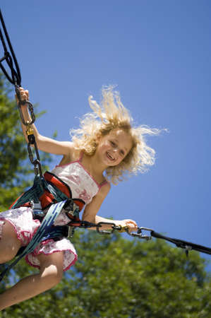 young girl bunji jumping securely on trampolineの写真素材
