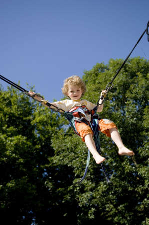 young girl bunji jumping securely on trampolineの写真素材