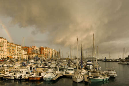 Port of Nice after the storm with rainbow and dark cloudsの写真素材