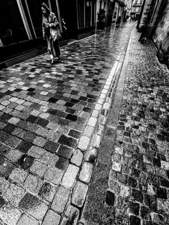 Unrecognizable people walking in a empty paved street in paris under the rainのeditorial素材