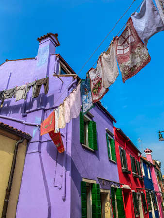 Laundry put to dry on a small traditional and very colorful square on Burano islandの写真素材