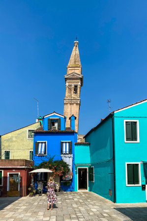 Colorful painted front houses in Burano with the leaning bell tower of San Martino church in the background, travel background, Italyの写真素材