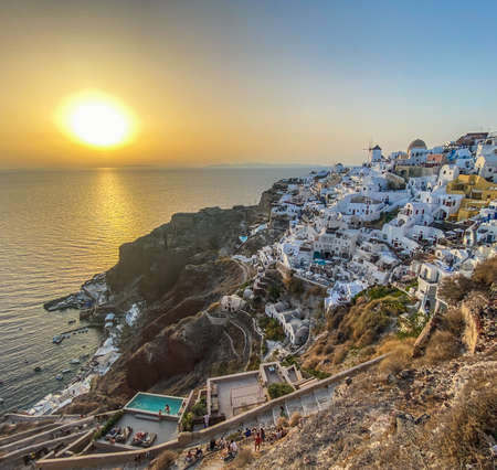 panoramic view of Oia village with traditional white architecture and windmills in Santorini island in Aegean sea at sunset, travel background, Santorini, Thera, Greeceの写真素材