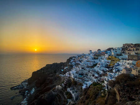 panoramic view of Oia village with traditional white architecture and windmills in Santorini island...