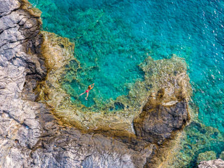 aerial view of transparent sea surface with unrecognizable people swimming in the sea, Amorgos, greeceの写真素材