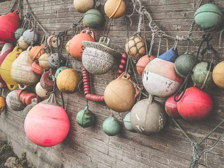 Many multicolored buoys hanging as decoration on a wooden wall in a garden