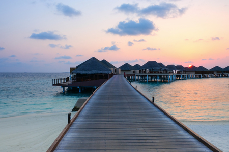 Sunset and water bungalows, abstract vacation background. Image has grain or blurry or noise and soft focus when view at full resolution. (Shallow DOF, slight motion blur)の写真素材