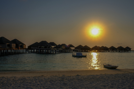 Sunset and water bungalows, abstract vacation background. Image has grain or blurry or noise and soft focus when view at full resolution. (Shallow DOF, slight motion blur)の写真素材