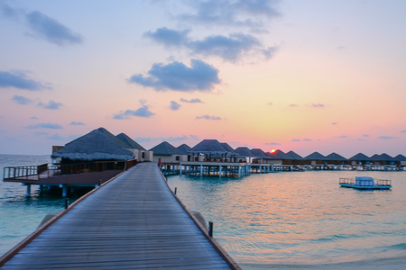 Sunset and water bungalows, abstract vacation background. Image has grain or blurry or noise and soft focus when view at full resolution. (Shallow DOF, slight motion blur)の写真素材