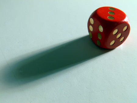Close up picture of a red dice with long shadowの写真素材