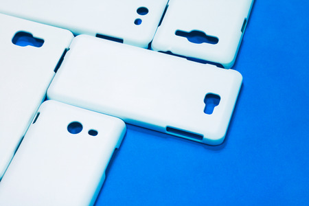 White phone cases on vivid blue background. Mobile cases or smartphone protector for your design.の写真素材