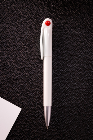 Dark pen and white card on dark background. Blank ballpoint pen for your design.の写真素材