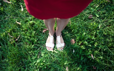 Girl with white sandals and red dress on green grassの写真素材