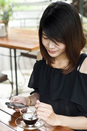 Beautiful Asian woman relaxing in coffee break with mobile phone の写真素材