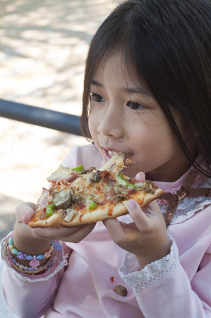Little Asian girl enjoy eating pizza の写真素材