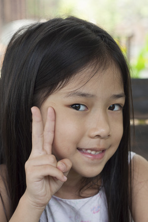 Little Asian girl with victory hand sign の写真素材