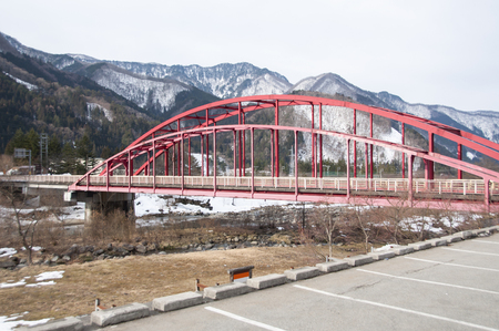 Old red steel bridge crossing the river in Japan.の写真素材