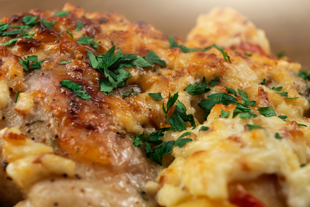 Chicken meat cooked in the oven with vegetables and a ruddy crust of cheese, decorated with chopped parsley.の写真素材