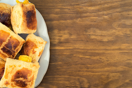 Buns of puff pastry, baked in the oven with a filling of soft cheese on a plate, view from above on...