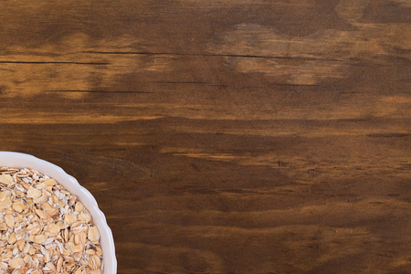 Oatmeal in a white plate on a wooden background, top view.の写真素材