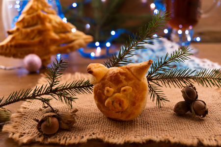 Christmas cookies made of puff pastry in the shape of a pig's head - a symbol of 2019 and a Christmas tree on the background of Christmas decorations.の写真素材