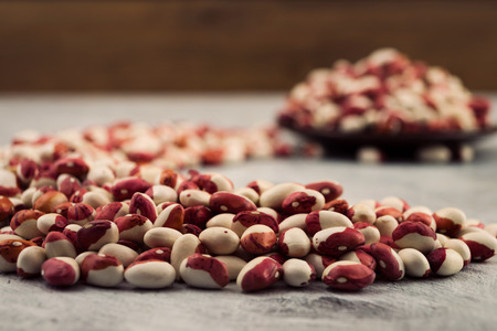 Seeds of two-color beans, scattered arc on the table, close-up, blurred background.の写真素材
