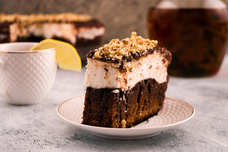 Piece of chocolate cake. A white layer of cream. Sprinkles of grated walnut. Lemon on the edge of...
