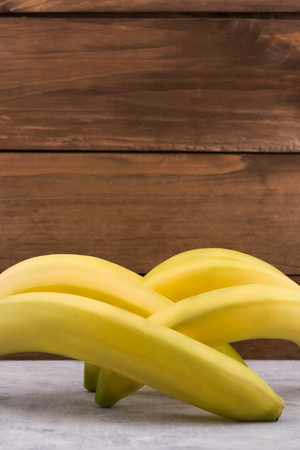 Tropical fruit. Whole banana fruit. Yellow peel. Vertical. Wooden background.の写真素材