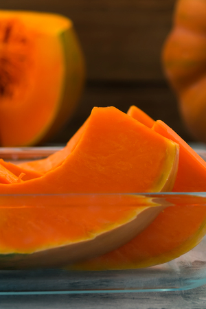 Pieces of orange pumpkin in a glass bowl. Vegetarian food. Raw vegetables. Orange pulp. Vertical.の写真素材