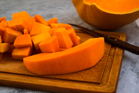 Cooking pumpkin. Cutting into pieces of ripe flesh. Kitchen cutting Board. Vegetarian food. Raw vegetables.の写真素材