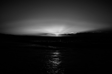 Black and white photo of sunset at sea. Reflection of sunlight in the water.の写真素材
