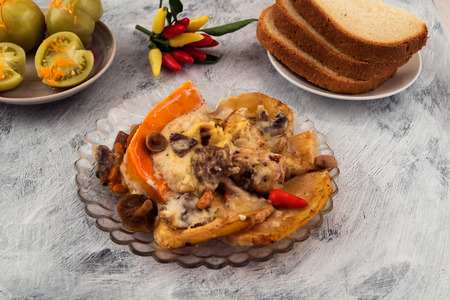 Portion of fried mushrooms with vegetables. Sliced potatoes and pumpkins. Small hot pepper. Marinated green tomatoes. Sliced white bread.の写真素材