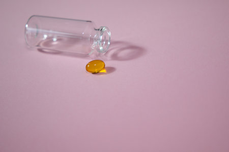 Yellow pills in a transparent bottle on a pink background. Copy space.の写真素材