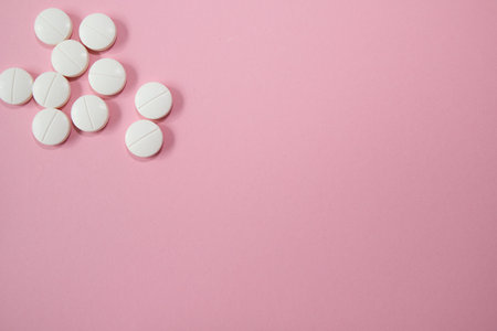 White pills on a pink background. Top view with copy space.