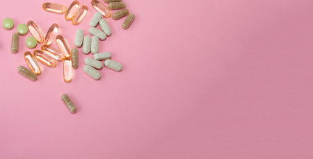Capsules and pills on a pink background with copy space.