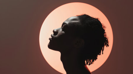 Silhouette of african american woman with closed eyes on orange backgroundの素材