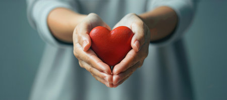 Close up of female hands holding red heart. Concept of health care and love.の素材
