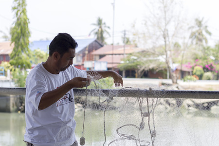 JERLUN KEDAH, MALAYSIA - 19/03/2016: Fisherman mending his fishing nets in kuala kedah, Malaysia.のeditorial素材