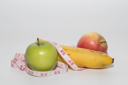 apple and banana with measuring tape on white backgroundの写真素材