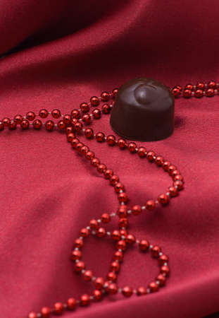 Chocolate and red beads on a satiny drapery
の写真素材