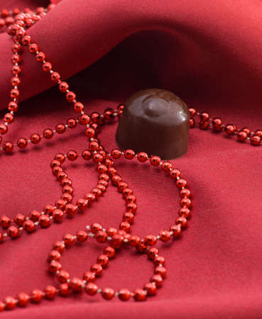 Chocolate and red beads on a satiny draperyの写真素材