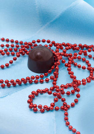 Chocolate and red beads on a blue satiny draperyの写真素材