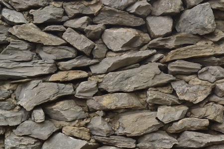 texture of a gray stone wall fence in the street of rough stones and cement