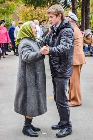 day of an elderly person in Russia, a young man dancing with an elderly woman in the park on an autumn afternoonのeditorial素材