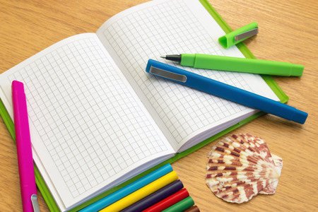 Notebook with pencils and pens on the table seashellの写真素材