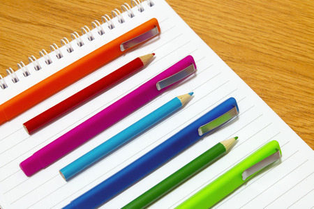 colored pens and pencils on a notepad on the tableの写真素材