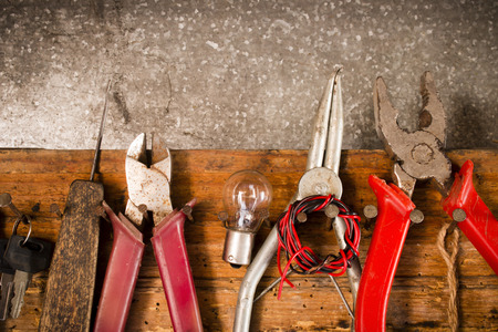 wrenches, pliers, bulbs, pliers, wire, rope on the nails on the old wooden standの写真素材