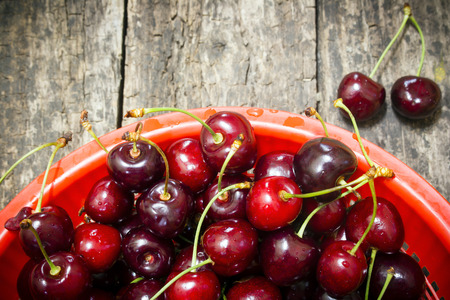 red bucket scoured rural cherries on a wooden tableの写真素材